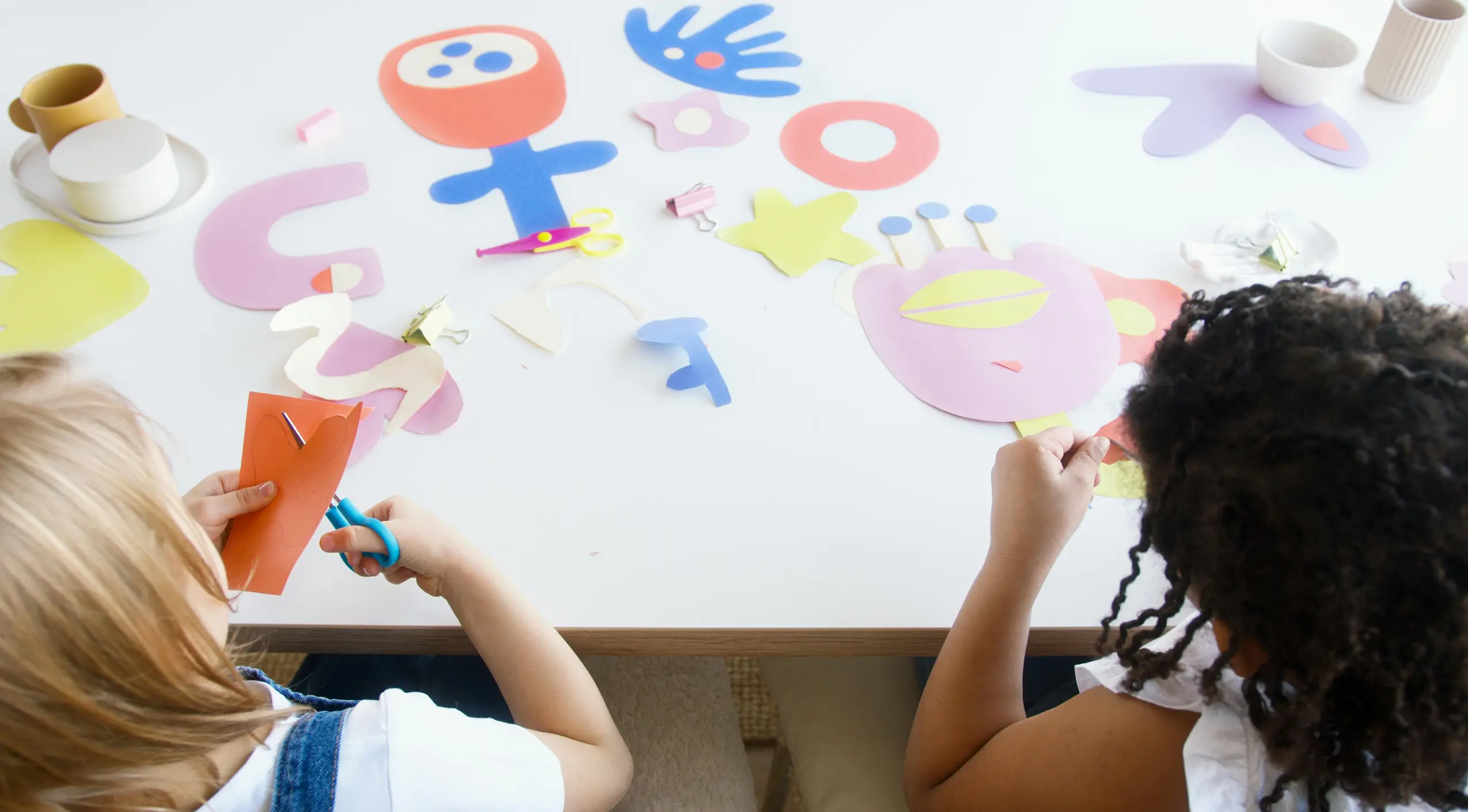 Kinder vertieft in kreative Bastelprojekte, umgeben von buntem Papier und Glitzer, erschaffen mit Freude und Stolz einzigartige Erinnerungsstücke an einen magischen Geburtstag.